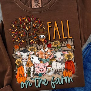 May include: Brown Comfort Colors sweatshirt with a colorful graphic. The graphic features the word "FALL" above a farm scene with cartoon animals, pumpkins, and the text "on the farm".