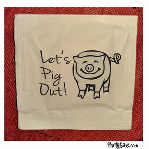 May include: White paper napkin with black text that says "Let's Pig Out!" and a cartoon pig with a smile.