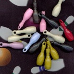 Puede incluir: Una colección de bolos de bowling en miniatura de varios colores, incluyendo rosa, marrón, beige, gris, azul claro, amarillo y rojo. Los bolos están hechos de plástico y tienen un acabado liso y brillante.