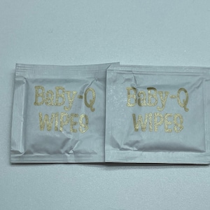 May include: Two individual packets of Baby-Q wipes, each with the brand name printed in gold lettering on a white background.