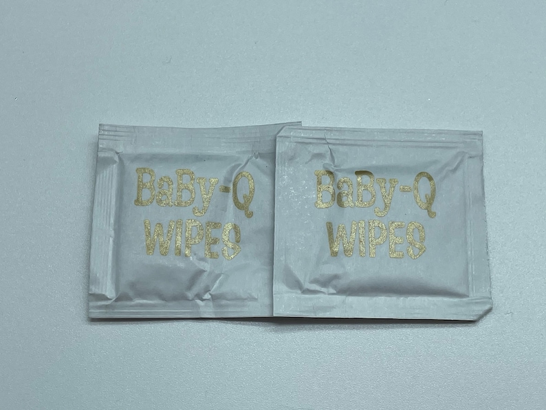 May include: Two individual packets of Baby-Q wipes, each with the brand name printed in gold lettering on a white background.