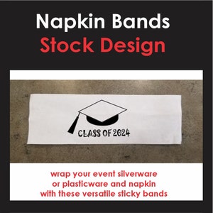May include: White napkin band with a black graduation cap and the text "CLASS OF 2024". Napkin bands are used to wrap silverware or plasticware for events.