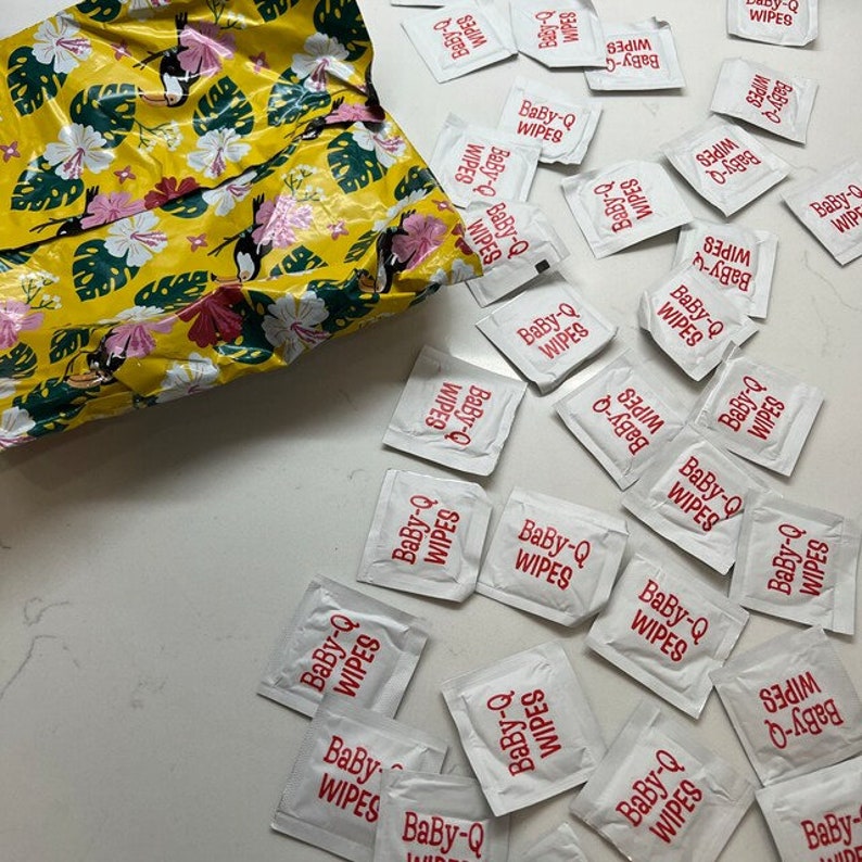 May include: A white plastic bag filled with individual packets of Baby-Q wipes. The packets are white with red text that reads "Baby-Q Wipes".