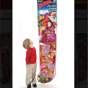 May include: A large red and white stocking filled with various toys and gifts. The stocking is hanging from a sign that reads "Super Colossal Christmas Stocking". A young child is standing next to the stocking, looking up at it.