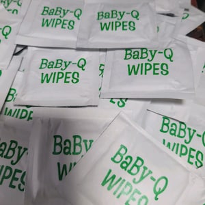 May include: A pile of white Baby-Q wipes with green text. The wipes are individually packaged in small, rectangular pouches.