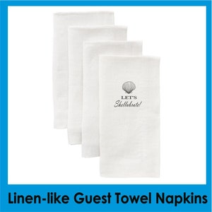 May include: Set of four white linen-like guest towels with a seashell design and the text "Let's Shell-abrate!"