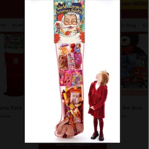 May include: A large red and white stocking filled with toys and gifts. The stocking is 8 feet tall and is being held up by a sign that says "World's Largest Christmas Stocking". A young girl is standing next to the stocking, looking up at it in awe.
