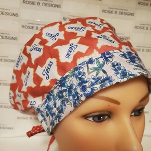 May include: A red and white scrub hat with a blue and white floral pattern. The hat has the word "Texas" printed on it multiple times. The hat is worn by a mannequin.