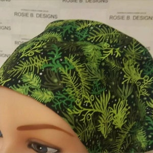May include: A black scrub hat with a green and white leafy pattern. The hat has a tie at the back.