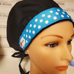 May include: Black scrub hat with a blue and white polka dot ribbon. The ribbon is tied at the back of the hat.