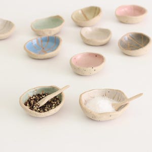 May include: A set of ten small, ceramic bowls in various colours, including blue, green, pink, and white. Each bowl has a unique design and is perfect for serving spices, dips, or condiments.