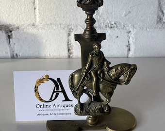 Op de afbeelding: Een messing boekenlegger met een figuur te paard met de inscriptie "WASHINGTON" aan de basis. De boekenlegger is gekroond met een kleiner figuur van een man in een jas. De boekenlegger staat op een wit oppervlak met een visitekaartje waarop "Online Antiques, www.onlineantiques.net, Antiques, Art & Collectibles" staat.
