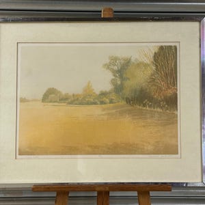 Puede incluir: Una taza de cerámica blanca con asa negra y el texto "But First, Coffee" en negrita negra. La taza está sobre una superficie de madera.