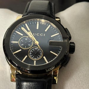 Gucci G-Chrono 44 mm roestvrijstalen vergulde kast met zwarte leren band.