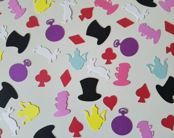 May include: A collection of colorful paper cutouts scattered across a light background. The shapes include hearts, diamonds, clubs, spades, pocket watches, teacups, top hats, and rabbits in various colors like red, black, purple, yellow, pink, white, and teal.
