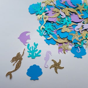 May include: Assortment of colorful paper cutouts in the shape of sea creatures, mermaids, and seaweed. The cutouts are made of glitter paper and are perfect for adding a touch of whimsy to any craft project.