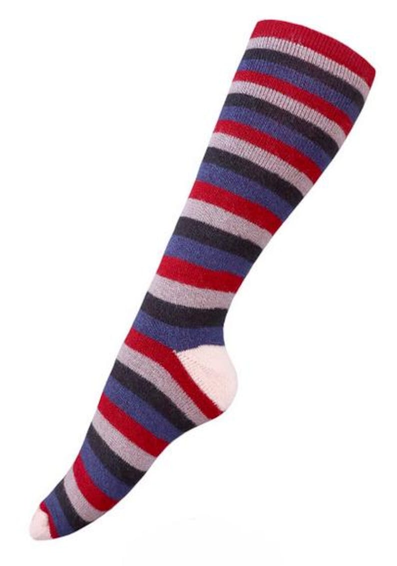 May include: Knee-high sock with horizontal stripes in red, gray, blue, and black. The toe and heel are light pink. The sock is angled diagonally from the bottom left to the top right.