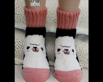 Puede incluir: Un par de calcetines de alpaca rosa y negro con una cara de alpaca blanca en cada calcetín. Los calcetines tienen un puño rosa y una banda negra alrededor del tobillo. Los calcetines están hechos por Fox Wire Farm Alpacas.