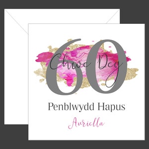 May include: A pink and gold watercolour birthday card with the number 60 in grey text. The text "Happy Birthday" is written in Welsh and the name "Aurelia" is written in pink.