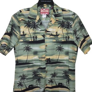 Puede incluir: Una camisa de manga corta con estampado de paisaje tropical. La camisa presenta un diseño de palmeras, surfistas y botes en tonos verdes, amarillos y negros. La camisa tiene cuello y está etiquetada como "RJC".