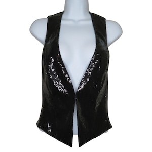 Op de afbeelding: Een zwarte paillettenvest met een open voorkant. Het mouwloze vest is gemaakt van een glanzend, reflecterend materiaal. Het kledingstuk wordt gepresenteerd op een witte mannequin.