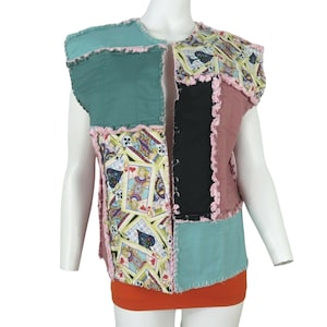 May include: A sleeveless vest made of patchwork fabric. The vest is made of different colors and patterns, including teal, pink, black, and a pattern of playing cards. The vest has a frayed edge.