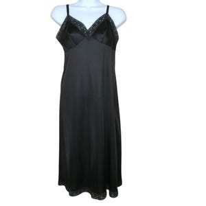 May include: A black slip dress with spaghetti straps and a V-neckline. The bodice is made of a shiny fabric, and the neckline and hem are trimmed with lace. The dress is displayed on a white mannequin.