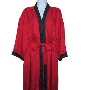 May include: A bright red robe featuring a subtle tonal leaf pattern throughout the fabric. The garment includes a solid black trim along the front opening and sleeve cuffs, along with a matching red fabric tie belt at the waist for closure.