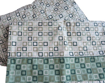 May include: A set of two green and white patterned bed sheets with a geometric design. The sheets have a white background with green and blue squares.