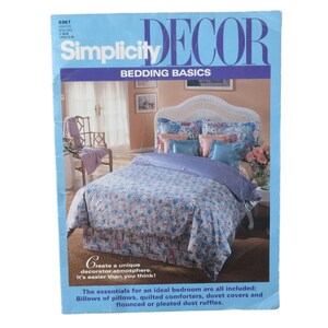 May include: A Simplicity Decor magazine cover featuring a white wicker headboard bed with a floral patterned duvet cover and pillows. The text on the cover reads "Simplicity Decor Bedding Basics".