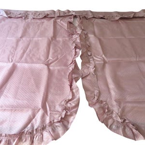 May include: A pair of pink sheer curtains with a dotted pattern and ruffled edges.