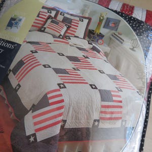 Pode incluir: Conjunto de edredão com um design patriótico. Apresenta bandeiras listradas em vermelho e branco e quadrados cinzentos com estrelas brancas. O conjunto inclui um edredão e fronhas. A roupa de cama é embalada em plástico transparente.