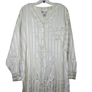 May include: Off-white, long-sleeved sleep shirt with vertical stripes. The shirt has a V-neck, a single chest pocket, and button closures. The brand name "SACIQUE" is visible on the label.