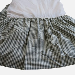 May include: A bed skirt with a white top and a green and white checkered pattern. The fabric is gathered, creating a ruffled effect. The skirt is designed to hang from the bed frame.