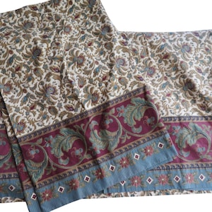 May include: A fabric textile featuring an intricate floral and vine pattern in shades of cream, tan, and muted blue. The lower section displays a wide border with a deep burgundy background, ornate teal leaf motifs, and a light blue striped edge.
