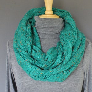 May include: Teal blue infinity scarf with a cable knit pattern and flecks of orange and yellow throughout.