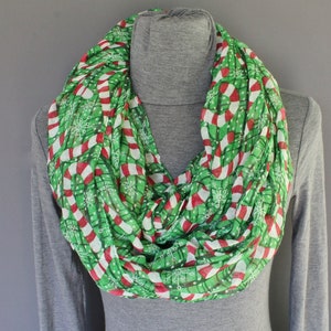 May include: A green and white infinity scarf with a candy cane and snowflake pattern.