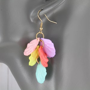 May include: A pair of dangle earrings with a cluster of pastel-colored plastic leaves. The leaves are in shades of pink, yellow, orange, and blue.