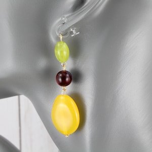 May include: A pair of dangle earrings with three beads. The top bead is light green, the middle bead is dark red, and the bottom bead is yellow.