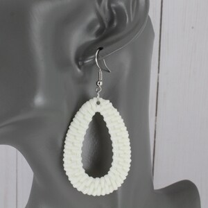 May include: White woven oval shaped dangle earrings with silver hooks.