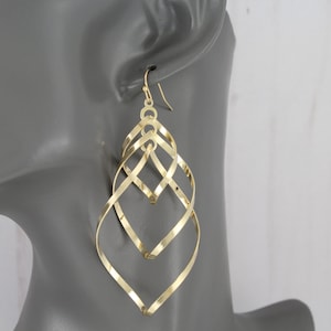 May include: Gold-toned, long, dangling earrings with a twisted, geometric design. The earrings are made of multiple thin, interwoven metal strands.