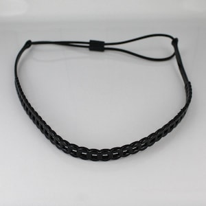 May include: A black headband with a woven design. The headband is adjustable with a black cord and a sliding adjuster. The band is made of a flexible material and is designed to fit comfortably around the head.