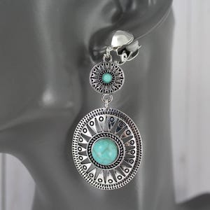 May include: Silver tone clip-on earrings with turquoise stones and a circular design.