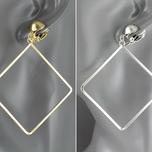 May include: A pair of large, thin, square-shaped hoop earrings with a clip-on mechanism. One earring is finished in a polished gold tone, while the other is finished in a polished silver tone. Both earrings feature a simple, open-frame design.