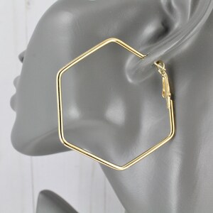 May include: Gold hexagonal hoop earrings with a hinged closure.