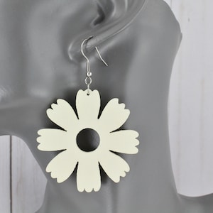 May include: A pair of cream-colored flower-shaped earrings with a silver hook.