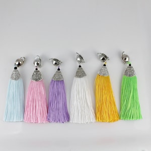 May include: Six pairs of colorful tassel earrings with silver metal tops. The tassels are in shades of light blue, pink, purple, white, yellow, and green.