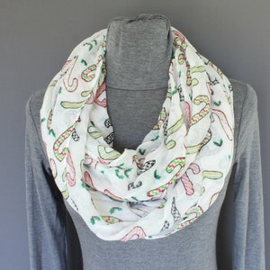 May include: White infinity scarf with a repeating pattern of candy canes and holly leaves.