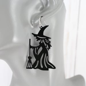 May include: Black witch silhouette earrings with a broom and hat. The earrings are made of metal and are a fun and spooky accessory for Halloween.