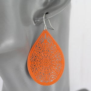 May include: Orange teardrop-shaped earrings with a delicate, intricate, laser-cut design.